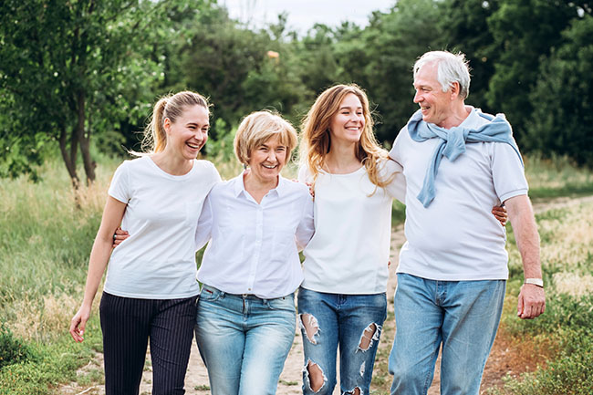 Older parents enjoying an outdoor walk with their adult daughters, illustrating family connections across generations.