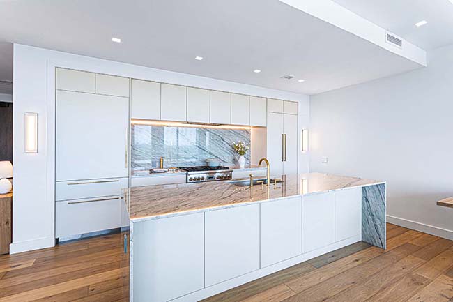Kitchen with a large island, white cabinetry, and stone backsplash at JW Marriott Residences Reston Station